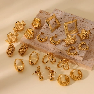 Macro shot of assorted gold earrings with geometric textures on stone background