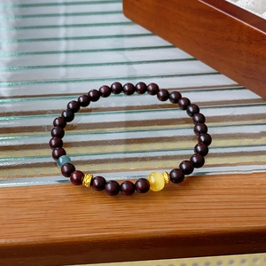 Detail view of dark red sandalwood beads with yellow amber and blue crystal accents