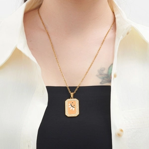 Detail of gold rectangle pendant necklace with smiley face and rhinestones on a model