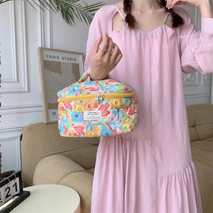 Trousse à maquillage matelassée avec motifs cœurs et smileys tenue en main