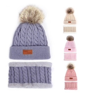 Close-up of cable knit beanie and neck warmer set with faux fur pom pom and fleece lining