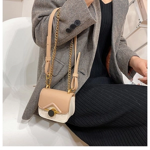 Mini borsa a tracolla beige e rosa indossata su un blazer grigio e gonna a pieghe nera