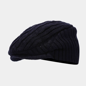Detailed close-up of dark blue cable knit beret hat with a short brim for autumn winter