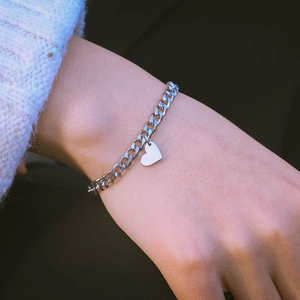 Minimalist silver heart pendant Cuban chain bracelet worn with a white knit sweater