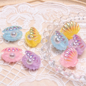 Macro shot of colorful pearlescent resin shell charms with pearls on white lace