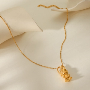 Artistic close-up of a gold 3D Sun Wukong pendant necklace on a minimalist wavy background
