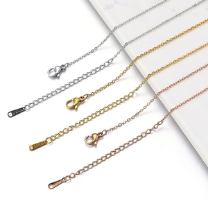 Three-color stainless steel extension chains with lobster clasps on marble surface