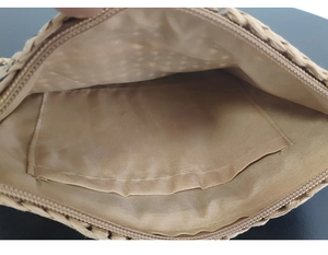 Internal view of the striped crochet clutch bag featuring beige lining and a zipper pocket