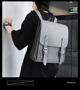 Gray vintage soft leather backpack with buckle straps shown in a realistic street setting