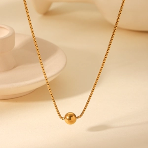 Detailed view of an 18K gold-plated stainless steel box chain with a round bead pendant