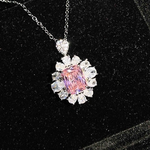 Detailed close-up of a square-cut pink gemstone pendant with a sparkling halo on black velvet