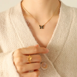 Bohemian gold butterfly pendant necklace and ring set on model in beige sweater