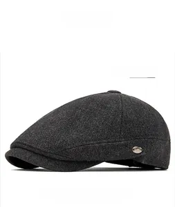 Detail of dark gray wool newsboy cap showing fine fabric texture and side metal emblem