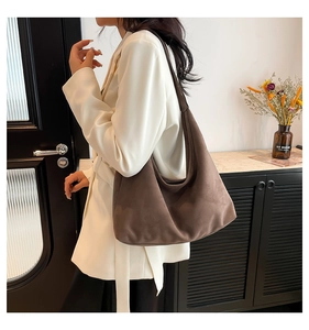 Brown matte suede tote bag carried by a model in a stylish modern home setting