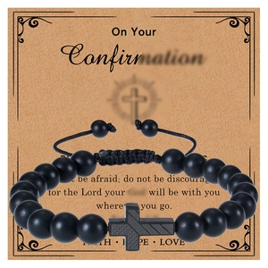 Détail d'un bracelet en perles noir mat avec une croix en métal sur carte cadeau