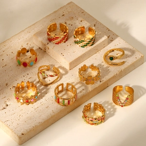 Collection of 18K gold plated stainless steel rings with colorful enamel on travertine base