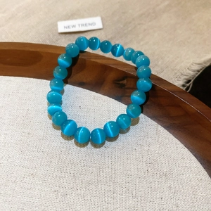 Primer plano detallado de una pulsera de cuentas de ojo de gato azul sobre madera