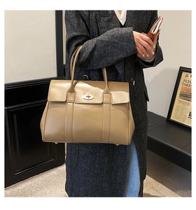 Detail of khaki leather tote bag worn with grey coat in a professional commute setting