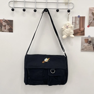 Detail of black canvas messenger bag featuring colorful planet embroidery and pockets