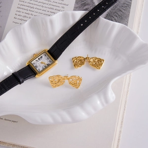 Boucles d'oreilles nœud dentelle dorées 18K et montre luxe en cuir présentées élégamment