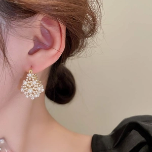 Close-up of gold-plated hollow pearl earrings worn on ear in French vintage style