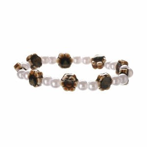 Close-up of ceramic flower beads and imitation pearls on a minimalist beaded bracelet
