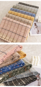 Detail showing various colors of plaid tasseled scarves with soft dot patterns