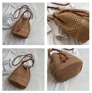 Detailed close-up of straw bucket bag texture and adjustable brown leather strap