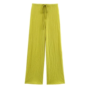 Detail of high-waist lime green wide-leg pants with textured seersucker fabric and drawstring