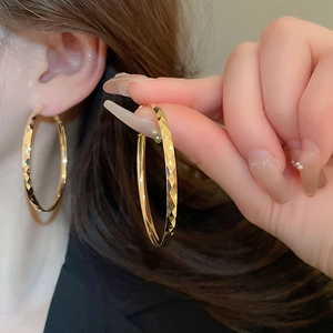 Detail of large gold hoop earring featuring exquisite diamond-cut textured metal finish