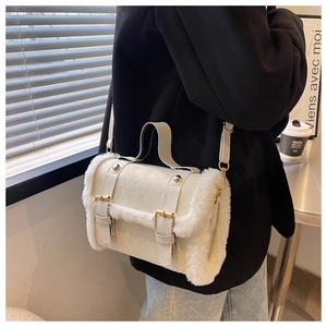 White plush trimmed handbag with gold buckles shown as a shoulder bag in a cafe setting