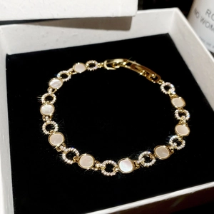 Détail du bracelet doré avec zircons et nacre blanche dans un coffret en velours noir