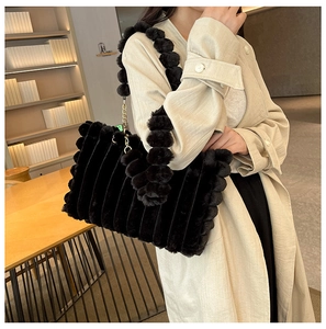 Detail of black fuzzy plush tote bag with wavy texture and gold chain shoulder strap