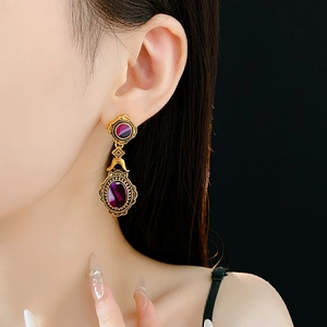 Detailed view of vintage gold earrings with purple oval gemstones on female model