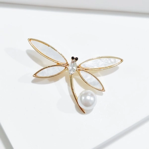 Detailed view of dragonfly brooch with golden wings, pearls and sparkling crystals