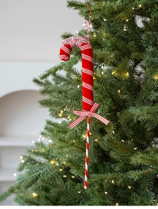 Close-up of red and white striped candy cane ornament with a bow on a Christmas tree