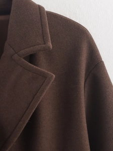 Vue détaillée des coutures du col et de l'épaule d'un manteau en laine marron foncé