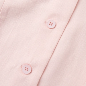Gros plan du gilet rose clair avec tissu texturé et boutons ronds en résine assortis