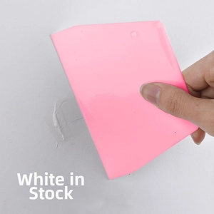 Pink plastic trapezoid scraper tool being used on white wall for putty application