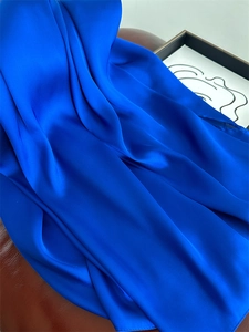 Close-up of blue satin silk scarf showing soft fabric folds and glossy smooth texture