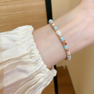 Close-up of a pearl bracelet with colorful beads on a wrist in natural lighting