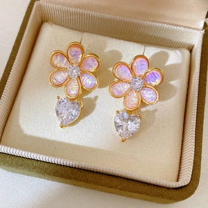 Detail of floral earrings with pink resin petals and heart-shaped zircon drop in a jewelry box