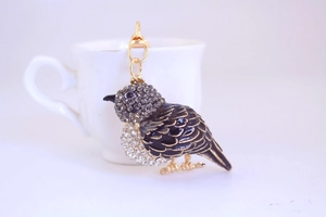 Close-up of a colorful kingfisher keychain with black enamel and sparkling rhinestones