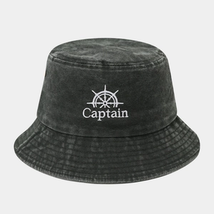 Detailed close-up of white Captain embroidery and helm logo on gray washed cotton bucket hat