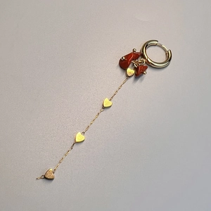 Detail of bohemian gold earrings with red natural stones and small heart charms