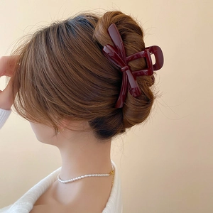 Detail of dark red bow hair claw clip showing a secure hold on a bun hair style
