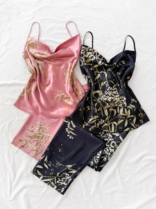 Flat lay detail of floral satin pajama sets featuring V-neck camisole tops and trousers