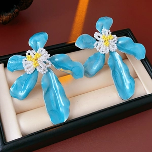 Gros plan détaillé de boucles d'oreilles fleurs en émail bleu dans une boîte à bijoux