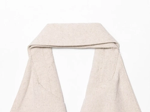 Dettaglio ravvicinato dello scollo all'americana sul gilet in lino beige con trama