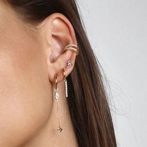 Close-up of model wearing gold earrings with purple butterfly studs and zircon tassels